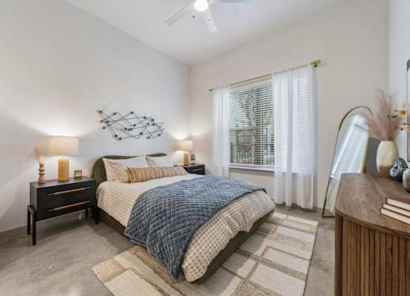 A bedroom with a bed, nightstand, and a ceiling fan.