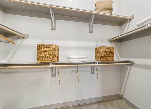 A white wall with three shelves and two baskets on them.