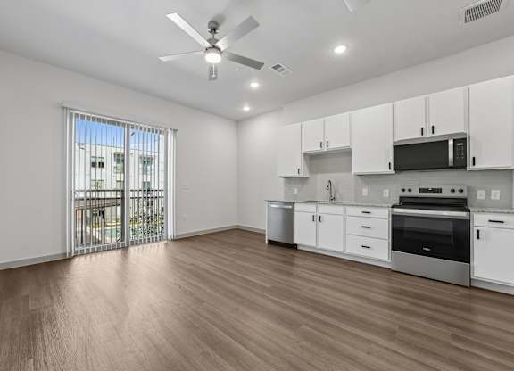 A kitchen with white cabinets and a wooden floor.
