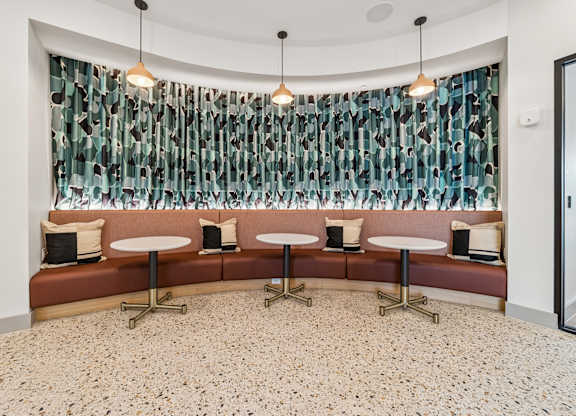 A room with a bench and a table with a curtain in the background.