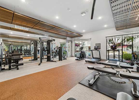 A gym with a variety of equipment including treadmills, weights, and exercise machines.