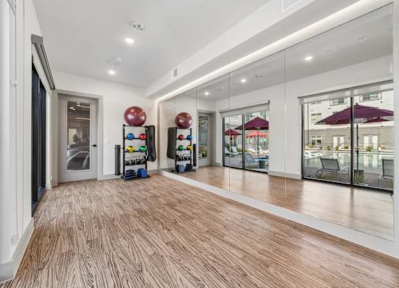 A long hallway with a wood floor and mirrors on the wall.