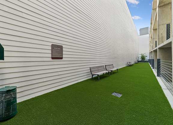 A white wall with a plaque and a green lawn.