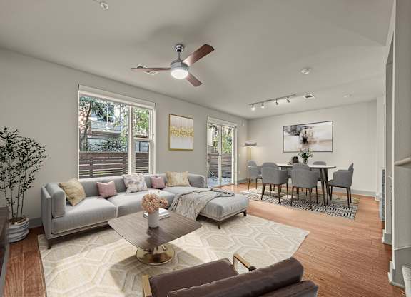 A living room with a grey couch, a coffee table, and a dining table with chairs.