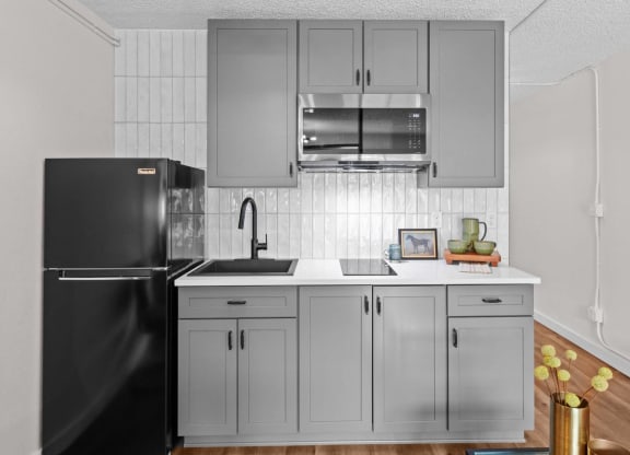 a kitchen with white cabinets and a black refrigerator