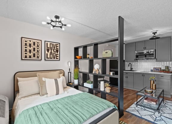 a bedroom with a bed and a kitchen with gray cabinets