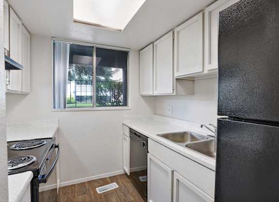 A kitchen with black appliances and white cabinets.