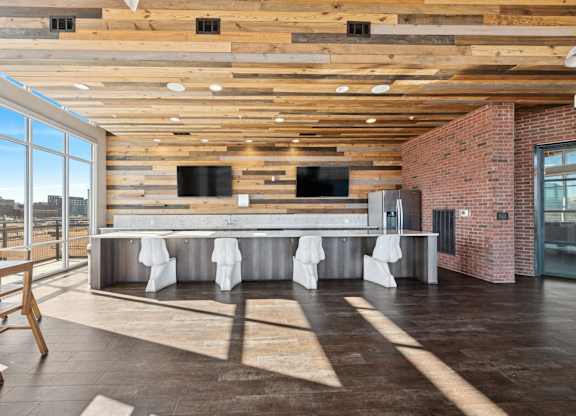 A modern kitchen with a long counter and a wooden ceiling.