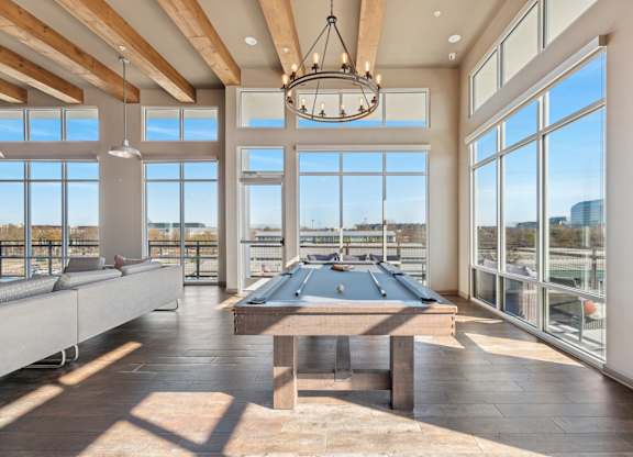 A large room with a billiard table and a view of the city.
