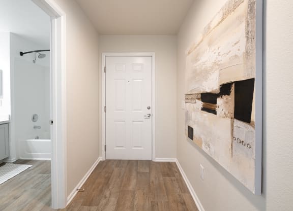 a hallway with a white door and a large painting on the wall