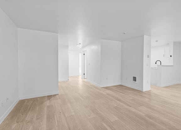 the living room and dining room of a new home with white walls and wood floors