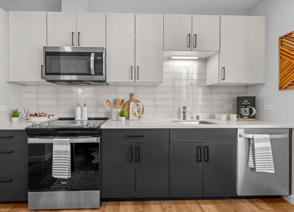 Gridline Apartments Kitchen with Stainless Steel Appliances and White Upper Cabinets and Gray Lower Cabinets