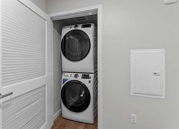 A white washer and dryer are stacked in a small laundry room.