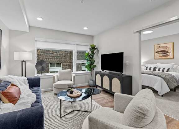 A living room with a grey couch, a black coffee table, and a television.