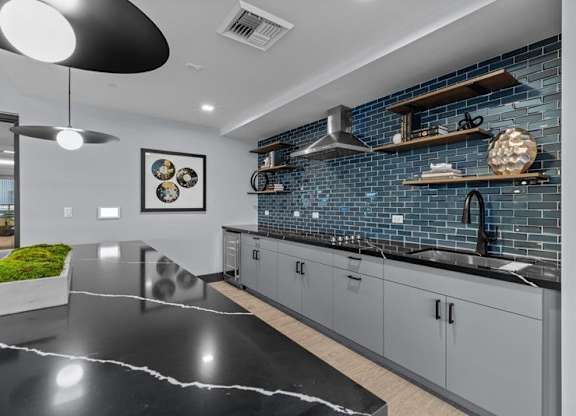 A modern kitchen with a black countertop and grey cabinets.
