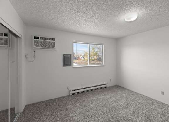 A room with a window and two air conditioning units.
