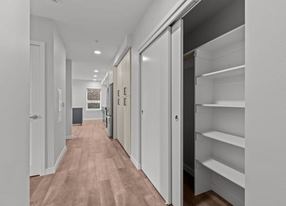 a long hallway with white closets and wood floors
