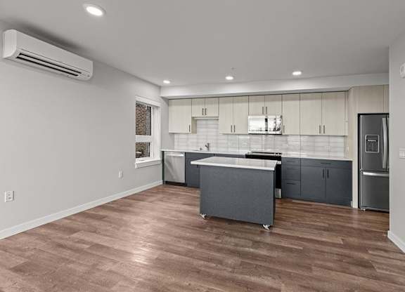 A kitchen with a refrigerator, sink, and cabinets.