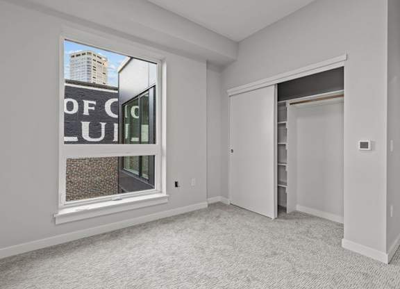 A room with a large window and a door leading to another room.