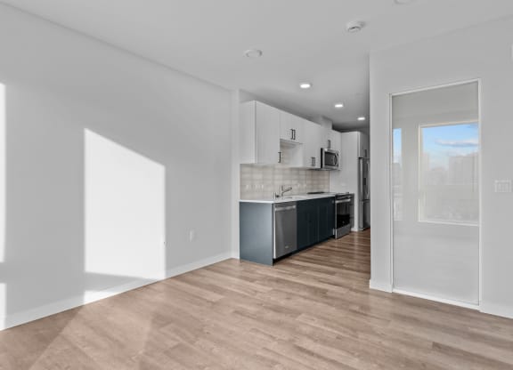the living room and kitchen in a new home with white walls and wood flooring