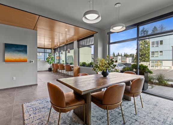 a dining area with a wooden table and chairs and large windows