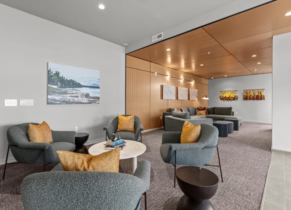 a lounge area with chairs and tables and a painting on the wall