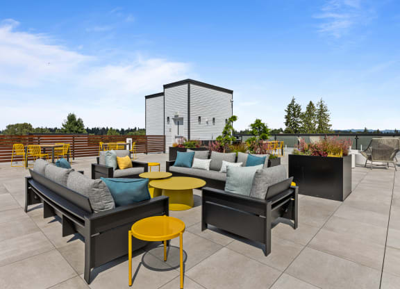 a rooftop patio with couches and tables on a sunny day