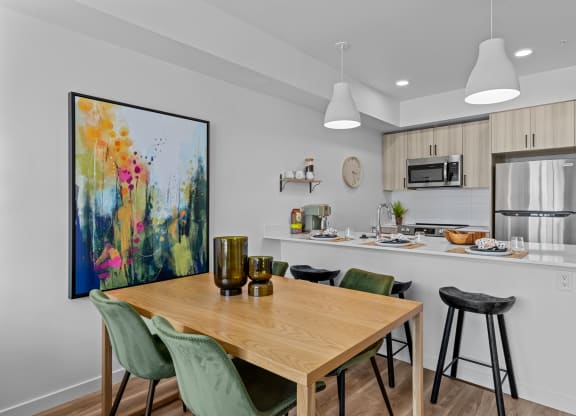 an open kitchen and dining area with a wooden table and bar stools