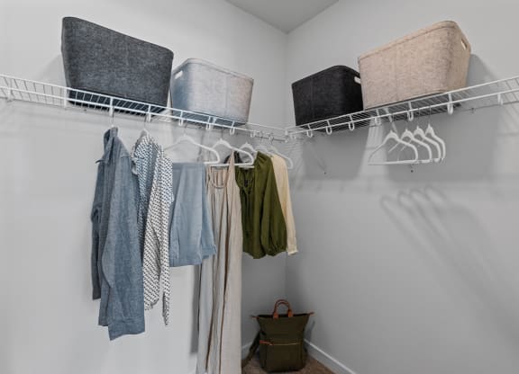 a walk in closet with clothes and baskets on the wall and a rack with towels