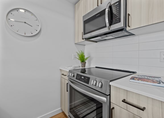 a kitchen with a stove and microwave and a clock on the wall