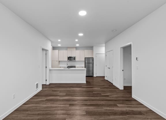 the living room and kitchen of a new home with white walls and wood floors