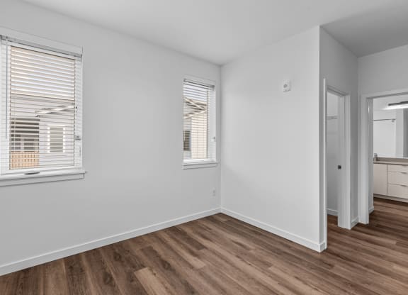 the living room of an apartment with white walls and wood flooring