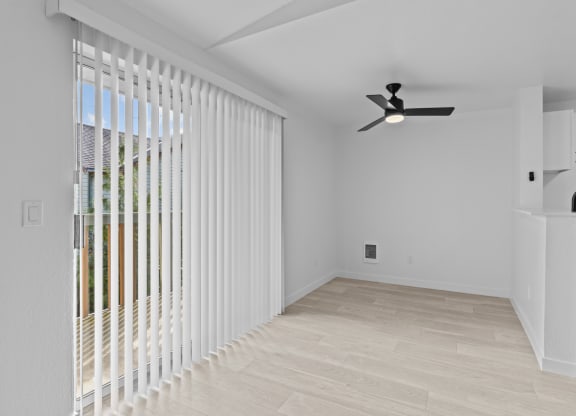 a living room with a large window and a ceiling fan