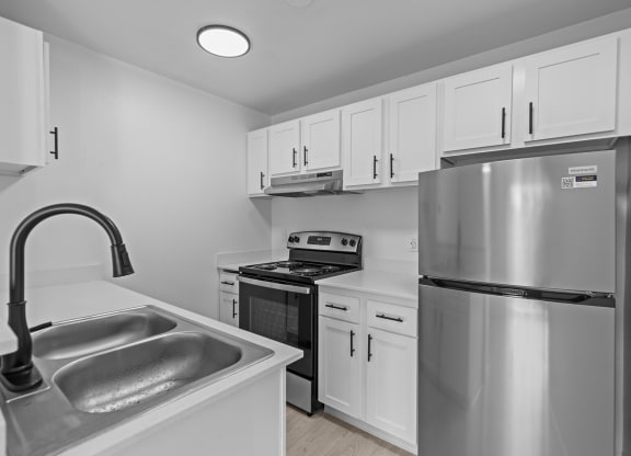 an empty kitchen with stainless steel appliances and white cabinets