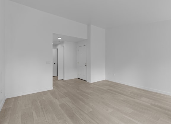 a living room and bedroom with white walls and wood flooring