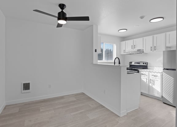 an empty kitchen and living room with a ceiling fan