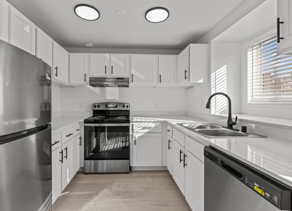 an empty kitchen with white cabinets and stainless steel appliances