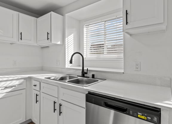 a kitchen with white cabinets and a sink and a window
