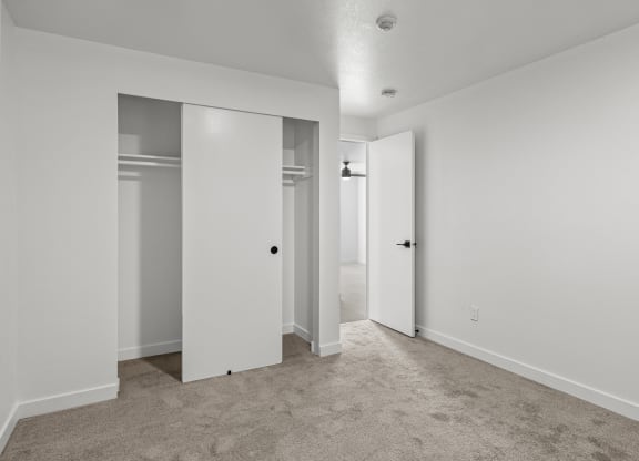 an empty bedroom with white walls and doors to closets