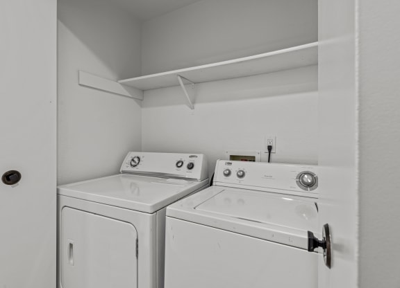 an empty laundry room with two washes and a dryer