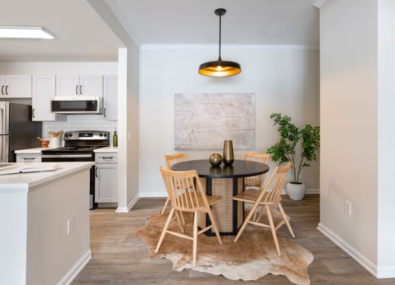 a dining area with a table and chairs and a kitchen in the background
