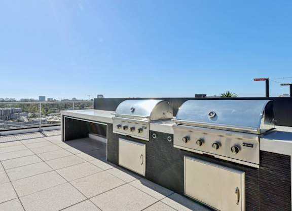 A row of outdoor grills on a rooftop patio.