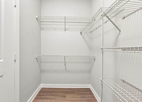 Empty white walk in closet with shelves.