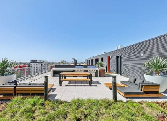 A rooftop patio with benches and plants.