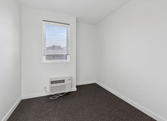 A room with a window and a fan on the floor.