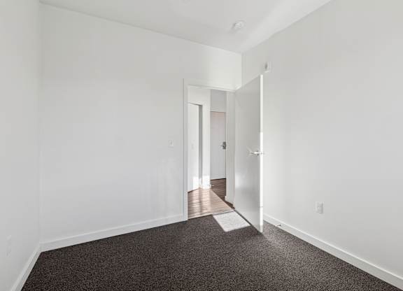 A hallway with a carpeted floor and white walls.