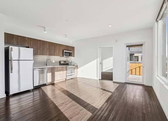A kitchen with white appliances and wooden floors.