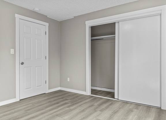 A room with a white door and a white closet with a glass door.