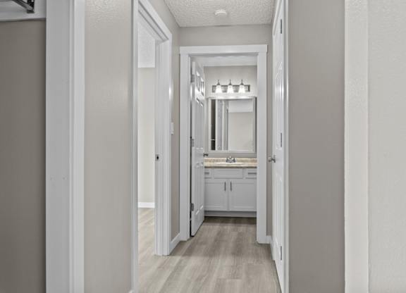 A white hallway leads to a kitchen.