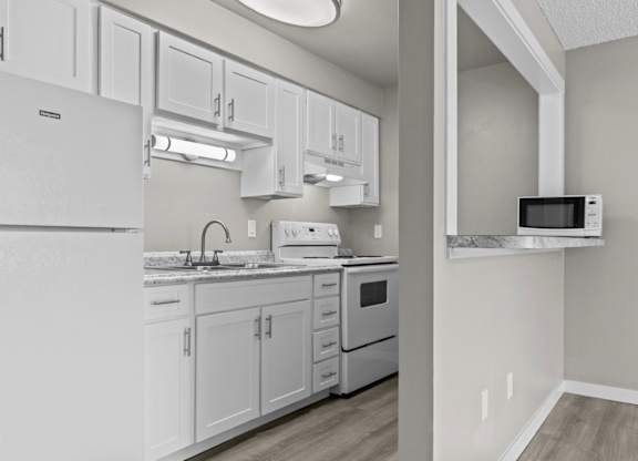 A kitchen with white cabinets and appliances.